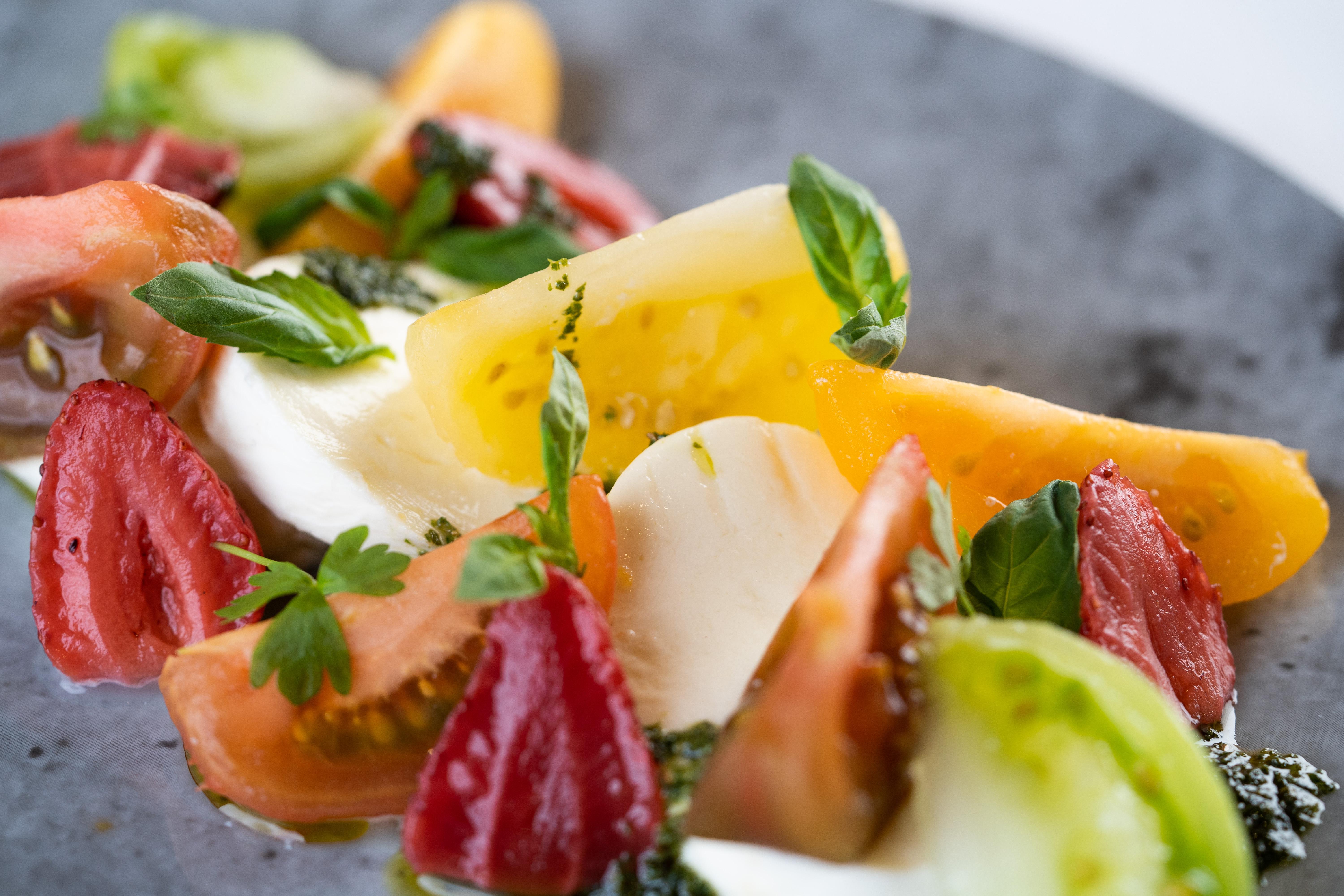 The Fitzwilliam Hotel Belfast Ngoại thất bức ảnh The photo shows a vibrant salad featuring slices of various tomatoes, including red, yellow, and green varieties. The tomatoes are paired with fresh mozzarella cheese and garnished with basil leaves. The dish is presented on a round, dark plate, high